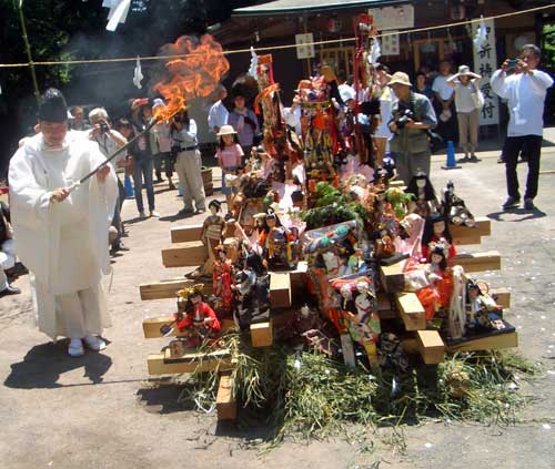 Il sacerdote dà fuoco al rogo su cui sono accatastate le bambole
